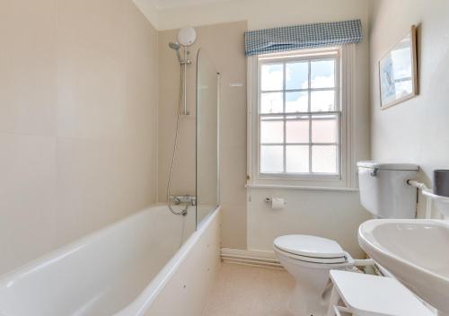 a bathroom with a toilet and a tub and a sink at Victoria Cottage in Woodbridge