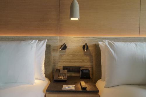 a bed with a phone on a table between two beds at Renaissance Cancun Resort & Marina in Cancún