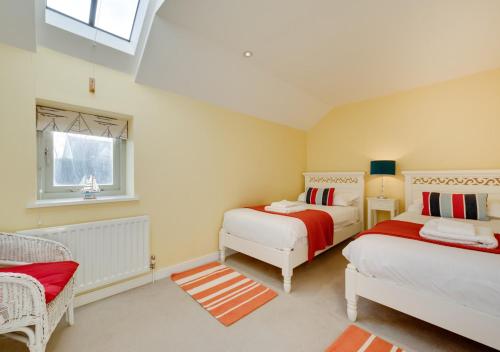 a bedroom with two beds and a window at West Barn Cottage in Aldringham