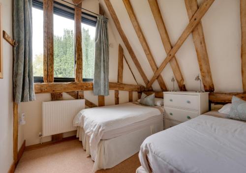 1 dormitorio con 2 camas y ventana en Wattisham Hall Barns, en Wattisham