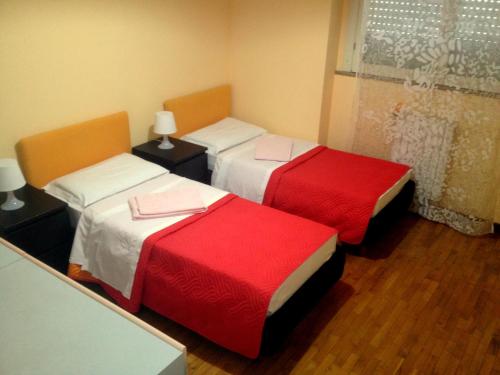 Habitación con 3 camas con sábanas rojas y blancas. en Star Hostel San Siro Fiera, en Milán