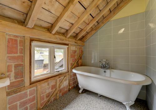 a bathroom with a bath tub and a window at Vale Farm Barns Sutton in Sutton