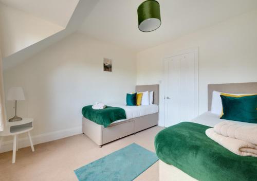 a bedroom with two beds and a green blanket at Tower Cottage in Walberswick