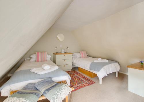 sypialnia na poddaszu z 2 łóżkami i komodą w obiekcie Wren Cottage w mieście Woodbridge
