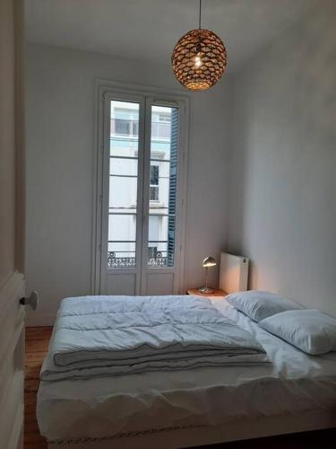 a white bedroom with a large bed and a chandelier at Le Victor Hugo - Hyper centre in Dieppe