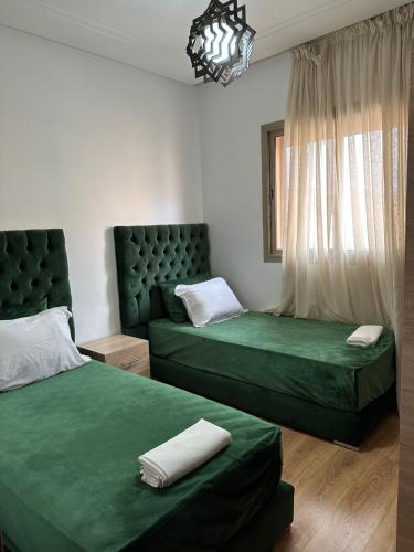 - une chambre avec 2 lits verts et une fenêtre dans l'établissement Appartement moderne avec piscine à Marrakech, à Marrakech