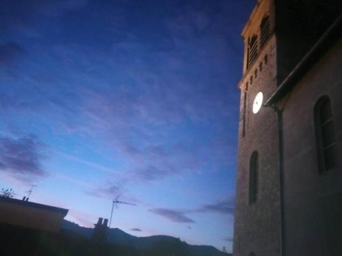 a building with a clock tower with a sky at Duplex dans village avec jardin in Claix