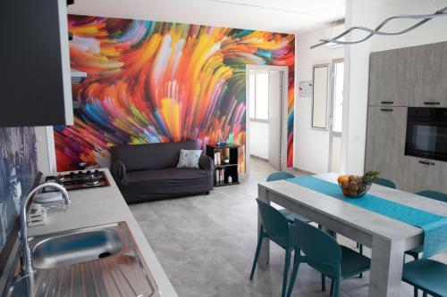 a kitchen and living room with a painting on the wall at Appartamento Profumo di Mare in Marina di Ragusa