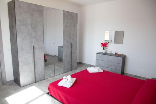 a bedroom with a red bed and a mirror at Appartamento Profumo di Mare in Marina di Ragusa
