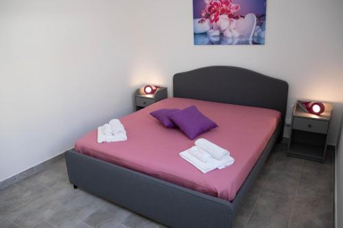 a bedroom with a bed with purple sheets and towels at Appartamento Profumo di Mare in Marina di Ragusa