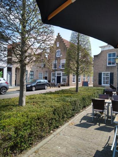 een bakstenen stoep met tafels en stoelen in een park bij Bed & Brasserie Het Kosthuys in Sint Maartensdijk