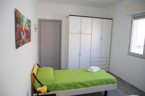 a bedroom with a green bed and white cabinets at Appartamento Profumo di Mare in Marina di Ragusa