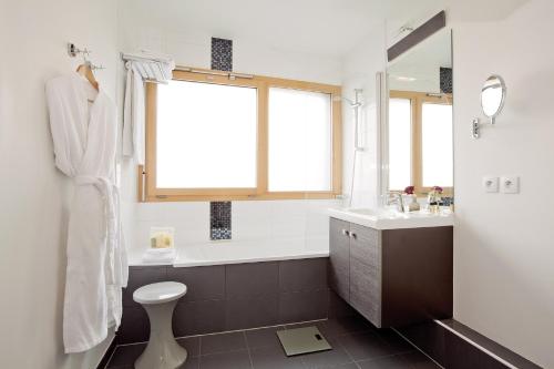 a bathroom with a tub and a toilet and a sink at Residhome Paris Issy Les Moulineaux in Issy-les-Moulineaux