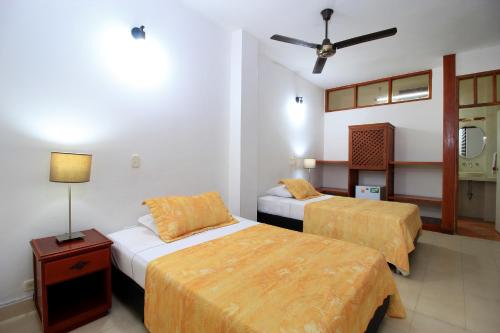 a hotel room with two beds and a ceiling fan at Hotel Emberá in Apartadó