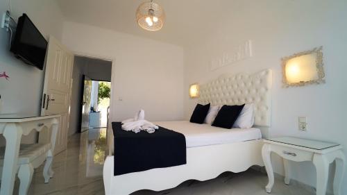 a white bedroom with a white bed and a television at Valtos View in Parga