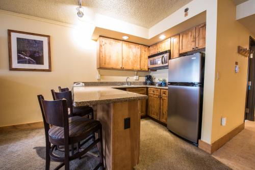 a kitchen with wooden cabinets and a stainless steel refrigerator at The Grand Lodge Hotel and Suites in Mount Crested Butte