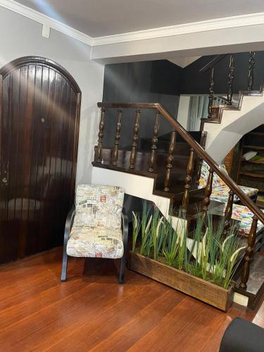 a living room with a chair and a staircase at HOSTEL FAMILIA ZANATTA in Caxias do Sul
