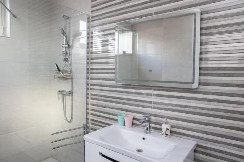 La salle de bains blanche est pourvue d'un lavabo et d'un miroir. dans l'établissement Apartmani Murić - Ena, à Bjelovar