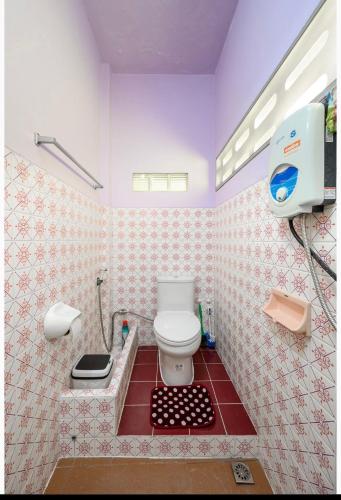 a bathroom with a toilet and a red tile floor at Lotus House in Ban Lo Long