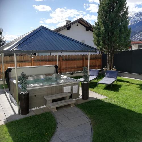 a hot tub in a yard with two chairs at Ferienwohnung am Waldweg in Kolsass