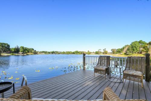 een houten terras met stoelen en uitzicht op het water bij Spring-Fed Lake Waterfront King Bed Suites Pet Friendly in Orlando