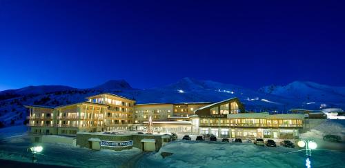 a large building in the snow at night at Grand Hotel Paradiso in Passo del Tonale
