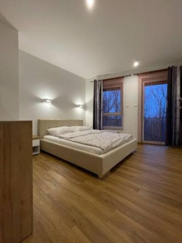 a large bedroom with a bed and two windows at Zacisze apartament in Zielona Góra
