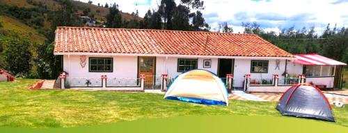 dos tiendas en el césped frente a una casa en Camping el triunfo, en Montecillo