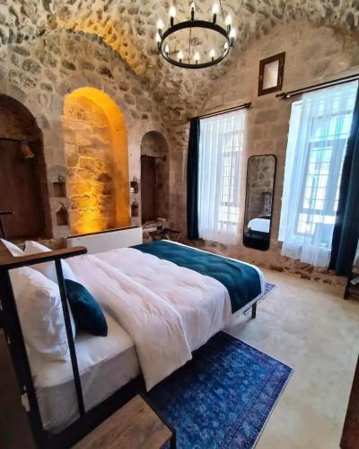 1 dormitorio con 1 cama grande en un edificio de piedra en TUĞMANER Small House AJAR en Mardin