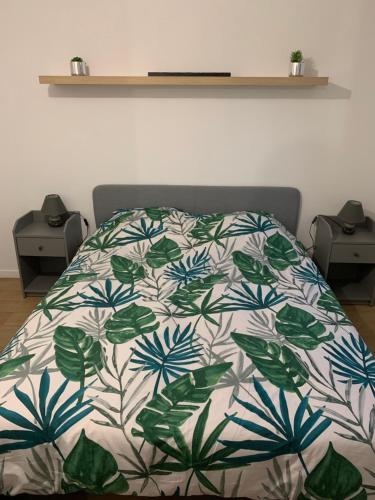 a bed with a green and white blanket on it at Logement à 20 min de Paris avec parking gratuit in Eaubonne