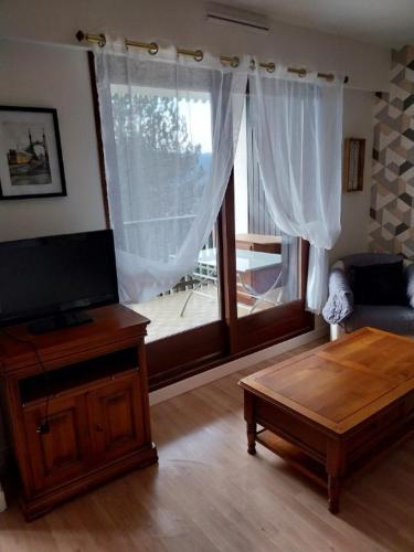 uma sala de estar com uma televisão de ecrã plano e uma mesa em f2 gerardmer em Gérardmer