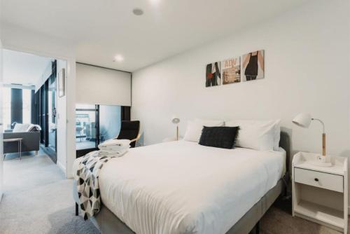 a white bedroom with a large bed and a window at Mountain views at Midnight in the heart of Canberra in Canberra