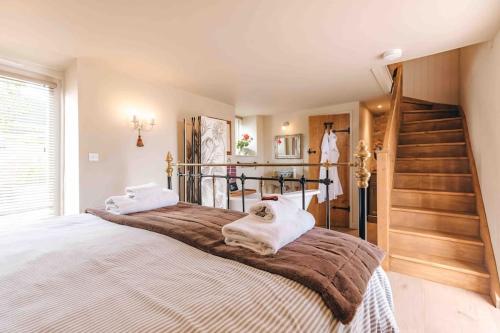 a bedroom with a large bed and a staircase at The Hayloft, Pillar Box Farm Cottages in Ludlow