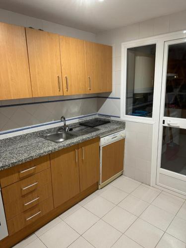 cocina con armarios de madera, fregadero y ventana en Luxurious Apartment 2 Bedroom 2 Bathroom Near Beach en Málaga
