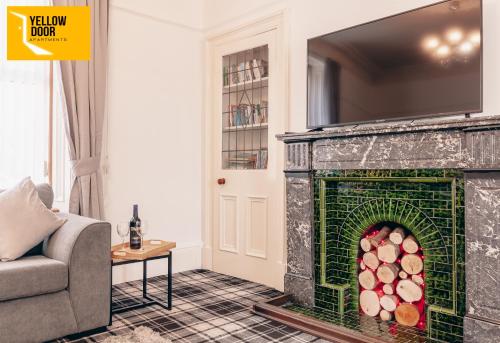 a living room with a fireplace with a tv above it at Stylish Central Eden Cottage with Courtyard & Free Parking in Dundee