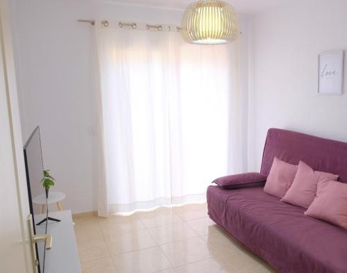 un sofá púrpura en una sala de estar con una gran ventana en EDEN RENTALS Caletillas Peace en Candelaria