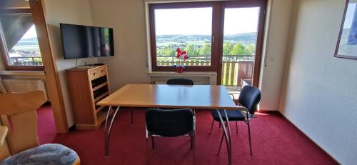 a room with a table and chairs and a television at Apartment mit Balkon in Kempfeld