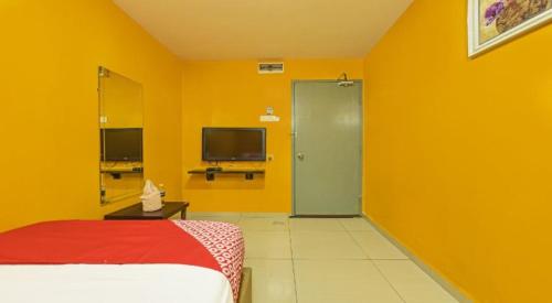 a yellow room with a bed and a green door at Juru Hotel in Bukit Mertajam