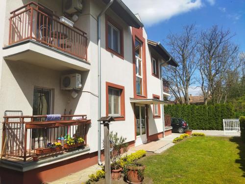 ein weißes Haus mit einem Balkon und einem Hof in der Unterkunft DORA Apartman in Palić