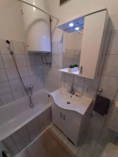 La salle de bains blanche est pourvue d'un lavabo, d'une baignoire et d'un miroir. dans l'établissement Apartman Posavac, à Crikvenica