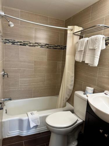 a bathroom with a toilet and a tub and a sink at Bestway Inn in Muncie