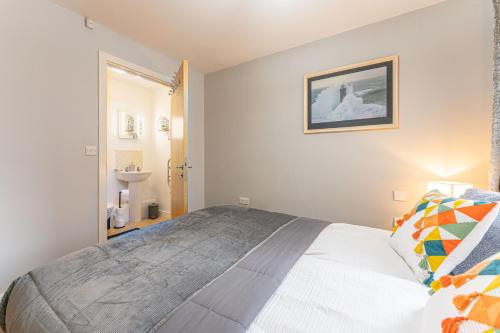 a bedroom with a large bed and a bathroom at CONTRACTORS & RELOCATION Friendly City Centre Flat - Disable People Welcome - Free Parking, Fast Wifi, Smart TV And 2 Bathrooms, 7min walk from Train Station! in Coventry