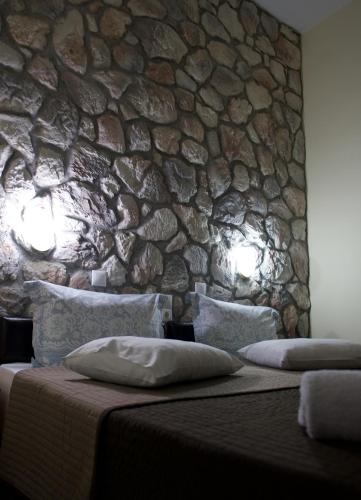 a bedroom with a stone wall and a bed with pillows at Rooms Batalogianni in Kalabaka