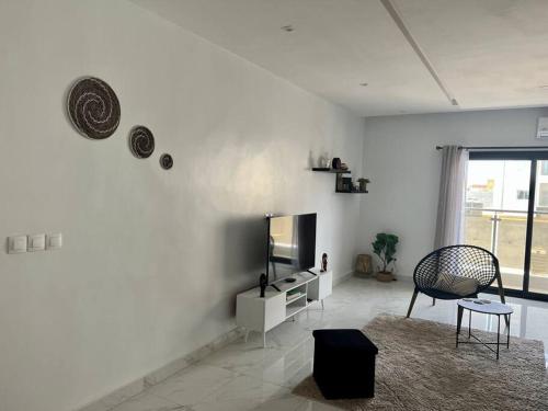 a white living room with a tv and a chair at 2br modern apartment in Almadies in Dakar