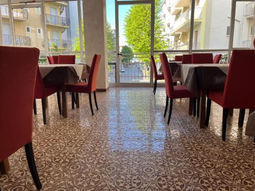 a dining room with tables and chairs and a window at Fellini Rimini in Rimini