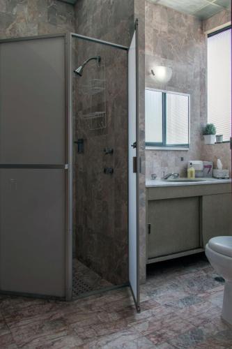 a bathroom with a shower with a toilet and a sink at Casa las Maravillas, hermosos jardines y alberca in Cuernavaca