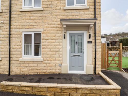 a brick house with a blue door and windows at Cheshire View in Buxton