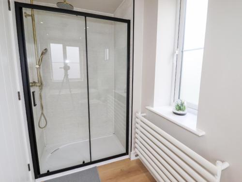 a glass shower in a bathroom with a window at Cheshire View in Buxton
