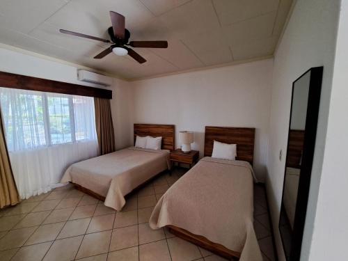 1 dormitorio con 2 camas y ventilador de techo en Hotel Las Espuelas, Bar & Restaurant en Liberia