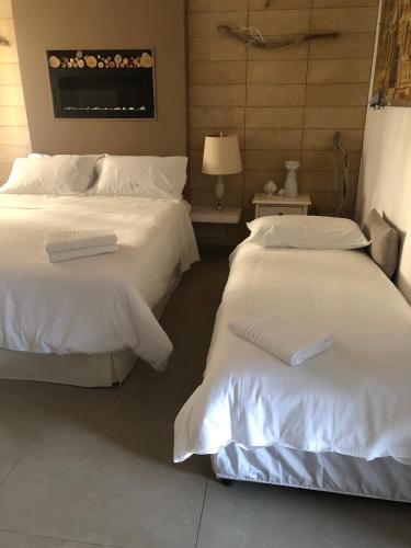 two beds in a hotel room with white sheets at ZEROstuni suite apartment in Ostuni
